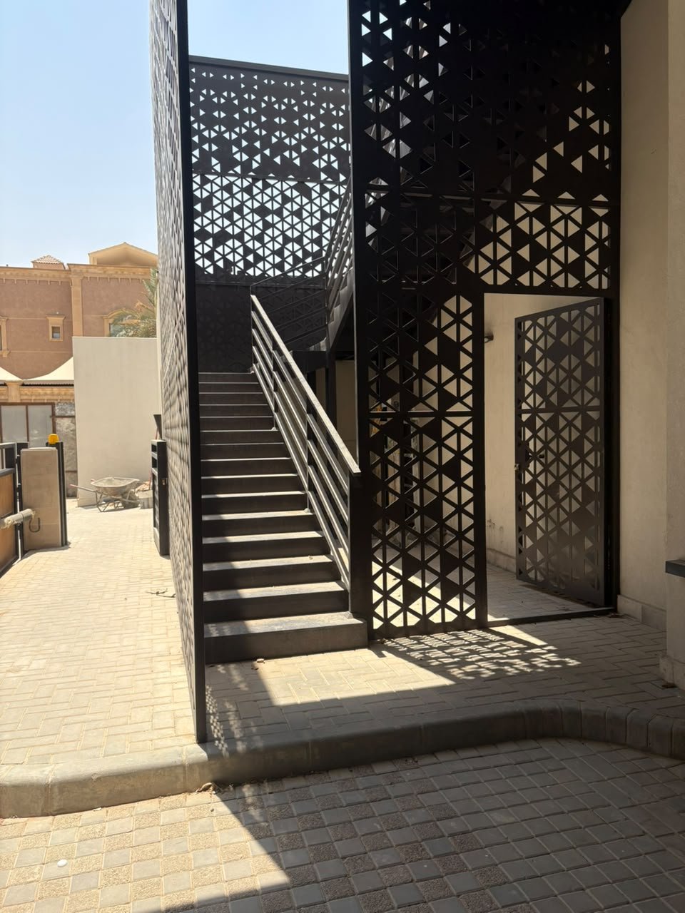 مدخل جانبي محاط بواجهة حديد مزخرفة ودرج خارجي